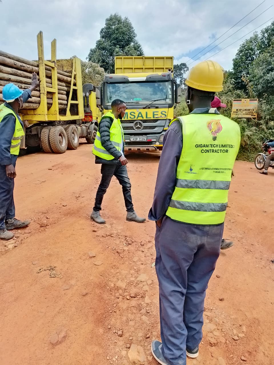 Gigam Tech crew receiving a delivery of wooden power poles on site